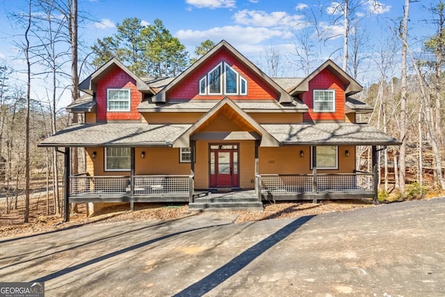 rustic home with covered porch and roof with shingles