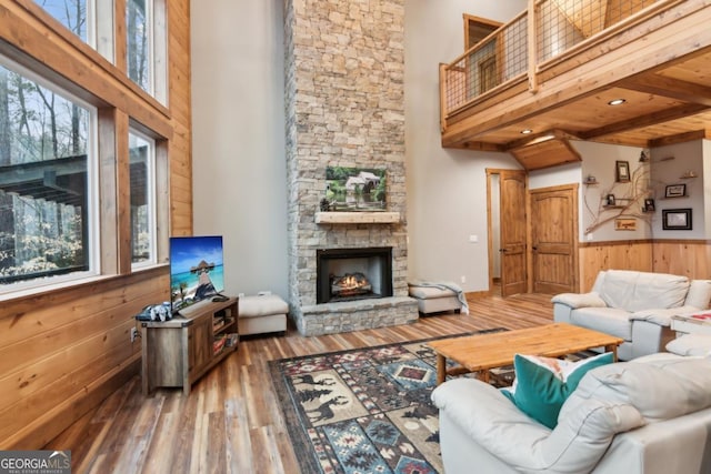 living area featuring a healthy amount of sunlight, wooden walls, a high ceiling, and wood finished floors