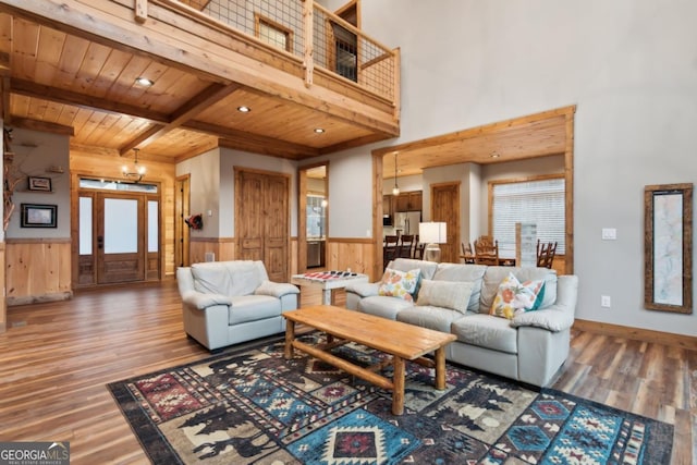 living room featuring wainscoting, wood ceiling, wood finished floors, beam ceiling, and a notable chandelier