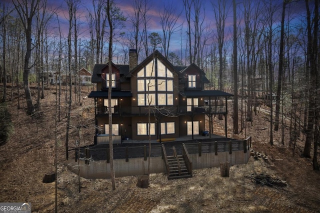 rear view of property with a chimney, a wooden deck, and stairs