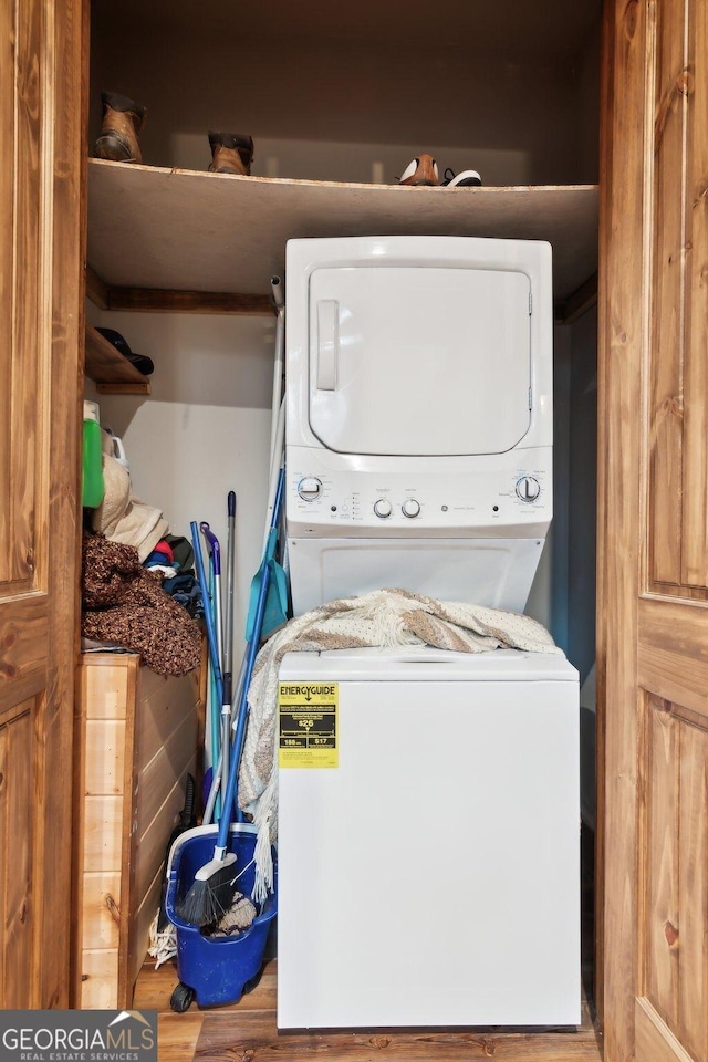 laundry room featuring wood finished floors, stacked washer and clothes dryer, and laundry area