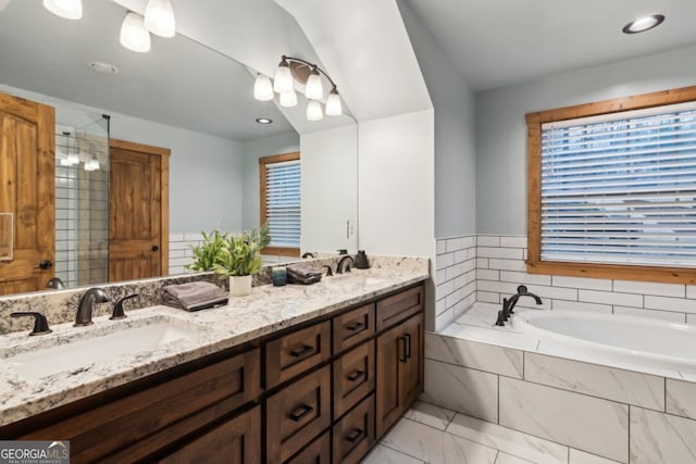 bathroom featuring marble finish floor, a garden tub, a sink, and double vanity