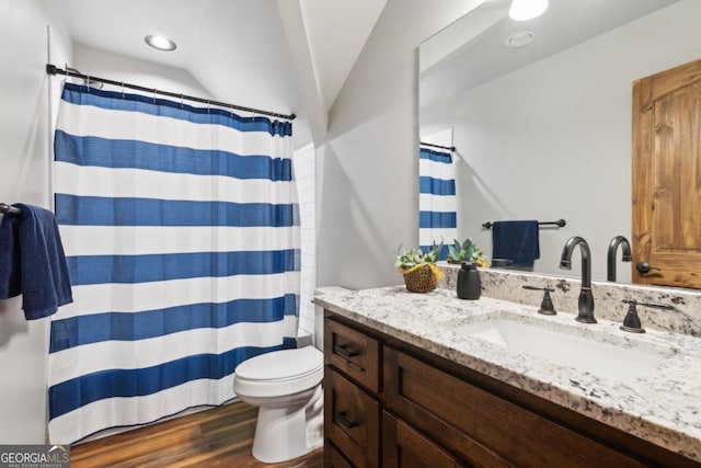 bathroom with curtained shower, toilet, wood finished floors, vanity, and vaulted ceiling