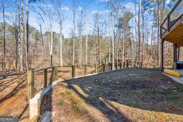 view of yard with a forest view and fence