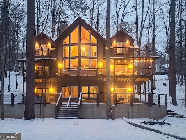 snow covered property featuring stairway, a chimney, and a balcony