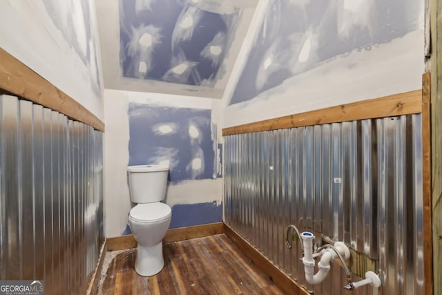 bathroom featuring toilet, baseboards, wood finished floors, and lofted ceiling