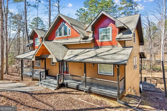 rustic home with a porch and roof with shingles