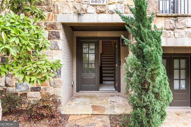 property entrance with stone siding and brick siding