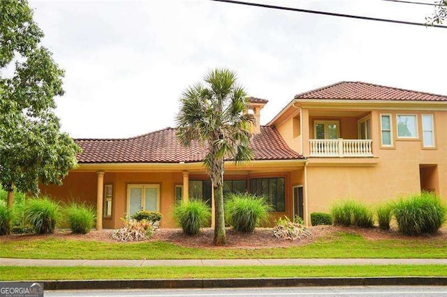 view of front of home with a front yard, a tile roof, and stucco siding