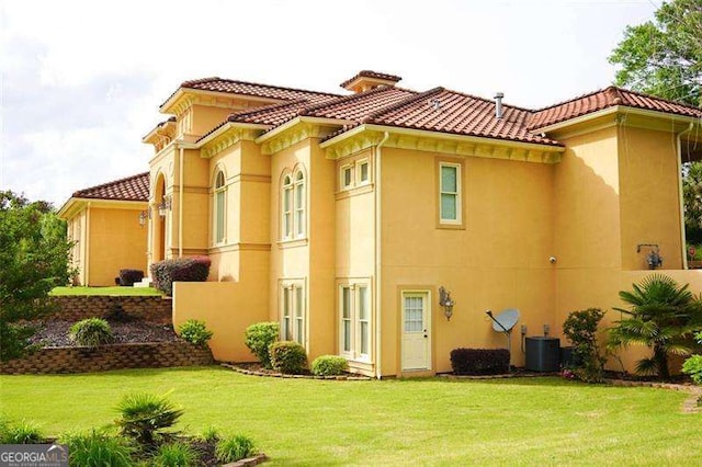 exterior space featuring central air condition unit, a yard, stucco siding, and a tiled roof