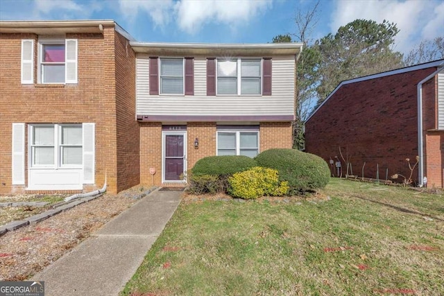 townhome / multi-family property with a front yard and brick siding