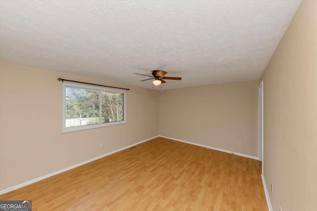 unfurnished room with baseboards, ceiling fan, a textured ceiling, and light wood finished floors