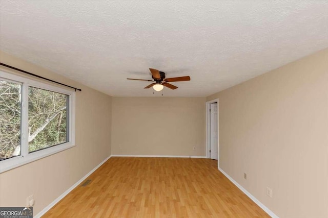 unfurnished room with baseboards, a textured ceiling, a ceiling fan, and light wood-style floors