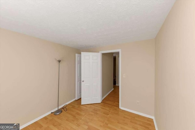 unfurnished bedroom featuring a textured ceiling, light wood-type flooring, and baseboards