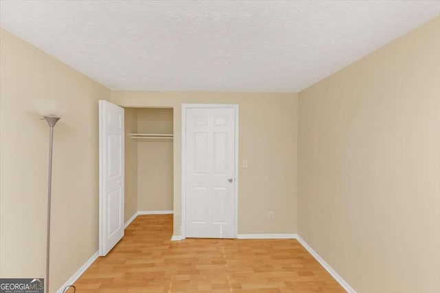 unfurnished bedroom with light wood-type flooring, baseboards, and a textured ceiling