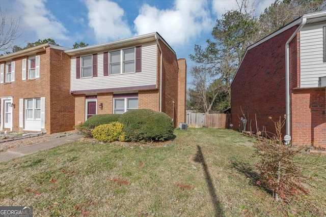 view of property exterior featuring a yard, fence, and brick siding