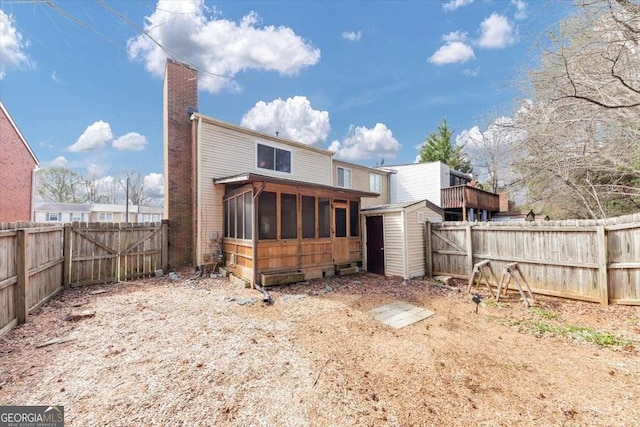 rear view of house with an outbuilding, a storage shed, a fenced backyard, and a sunroom