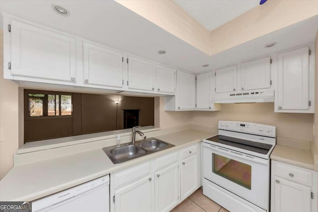 kitchen with white appliances, white cabinets, a sink, and under cabinet range hood