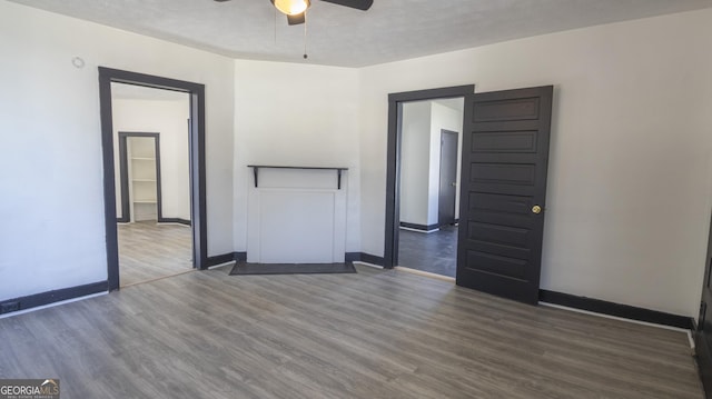 unfurnished room featuring a ceiling fan, baseboards, and wood finished floors