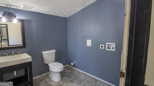 bathroom with visible vents, toilet, a textured ceiling, vanity, and baseboards