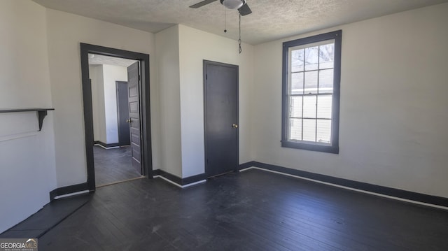 empty room with dark wood-style floors, a textured ceiling, a ceiling fan, and baseboards