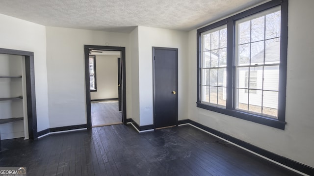 interior space featuring dark wood-style floors, a textured ceiling, and baseboards