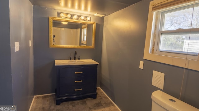 full bathroom with toilet, vanity, and baseboards