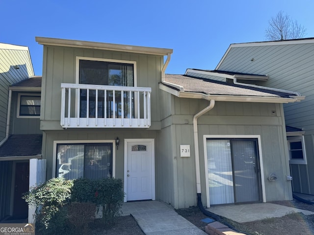 view of property featuring board and batten siding, roof with shingles, and a balcony