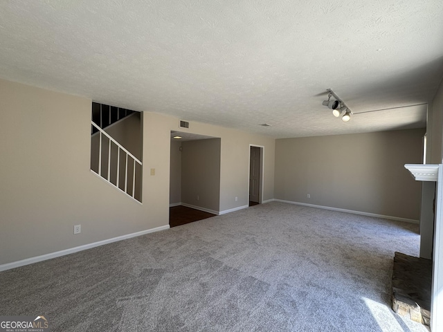 unfurnished living room with a textured ceiling, carpet floors, visible vents, baseboards, and stairs