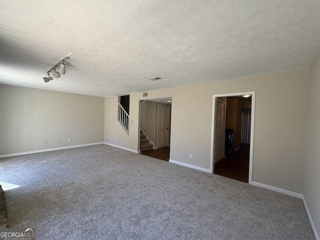 empty room with dark colored carpet, visible vents, baseboards, and stairs