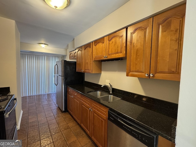 kitchen featuring appliances with stainless steel finishes, brown cabinetry, dark stone countertops, and a sink