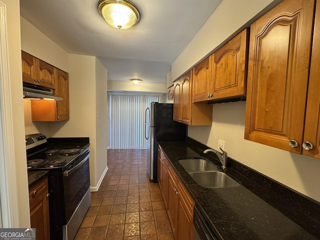 kitchen with brown cabinets, dark stone countertops, stainless steel appliances, under cabinet range hood, and a sink