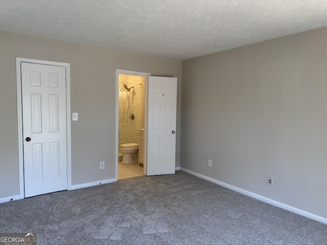 unfurnished bedroom with a textured ceiling, carpet floors, ensuite bathroom, and baseboards