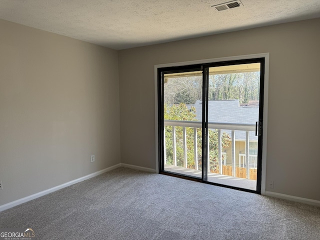 unfurnished room with carpet floors, baseboards, visible vents, and a textured ceiling