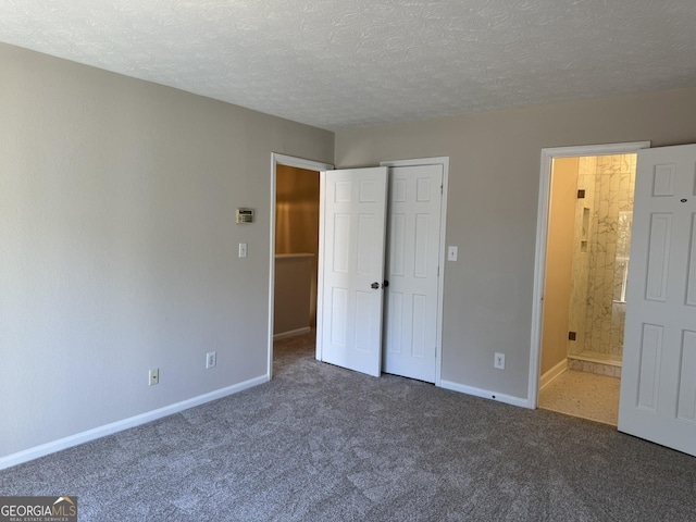 unfurnished bedroom featuring carpet, connected bathroom, baseboards, and a textured ceiling