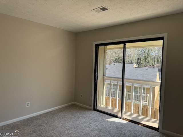 spare room featuring a textured ceiling, carpet floors, visible vents, and baseboards