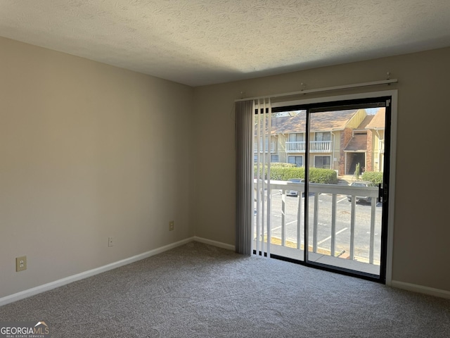 spare room with carpet, baseboards, and a textured ceiling