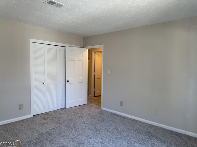 unfurnished bedroom with a textured ceiling, carpet flooring, visible vents, and baseboards