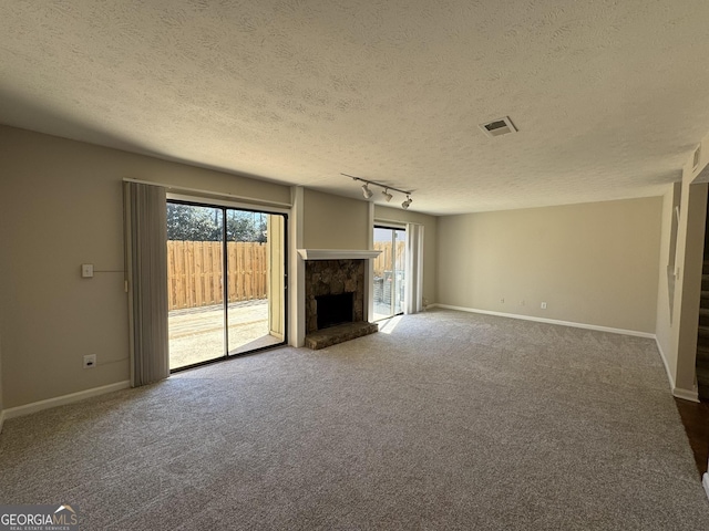 unfurnished living room with carpet, track lighting, a fireplace, and baseboards