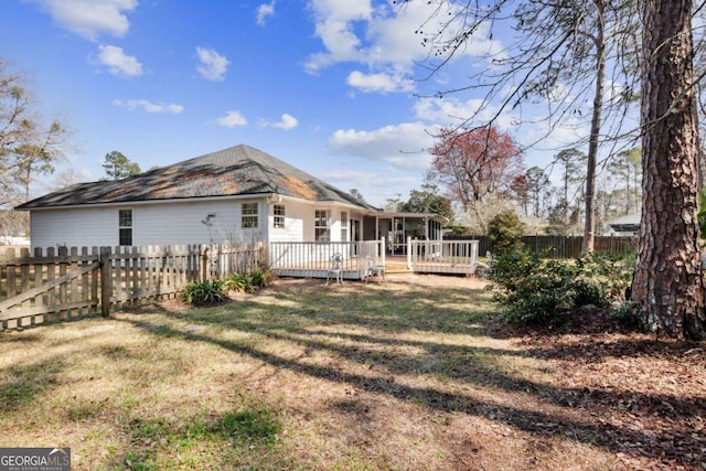 rear view of house with a sunroom, a yard, a fenced backyard, and a wooden deck