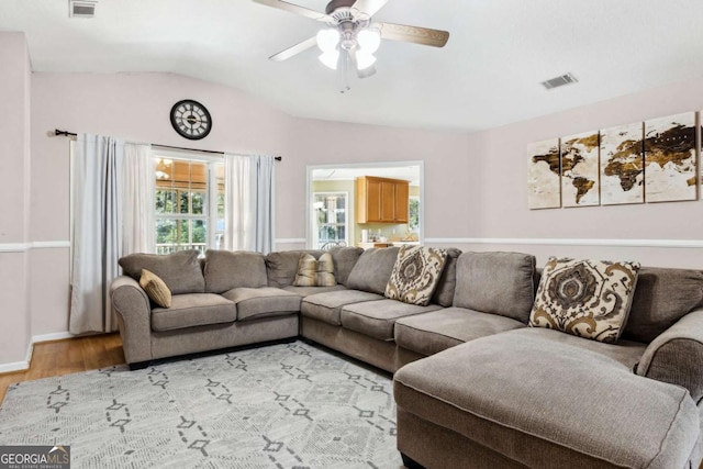 living area with light wood finished floors, visible vents, and vaulted ceiling