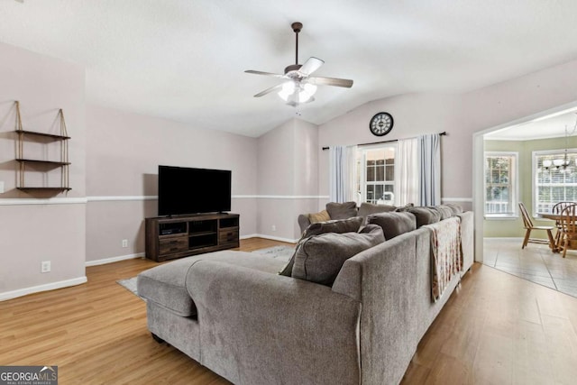 living room with a ceiling fan, lofted ceiling, baseboards, and wood finished floors