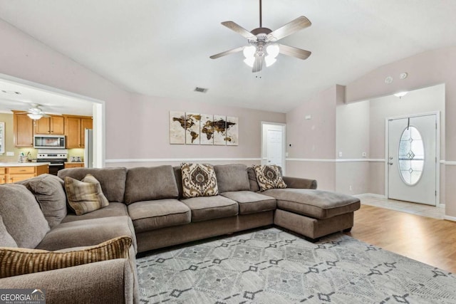 living area with baseboards, visible vents, a ceiling fan, lofted ceiling, and light wood-style flooring