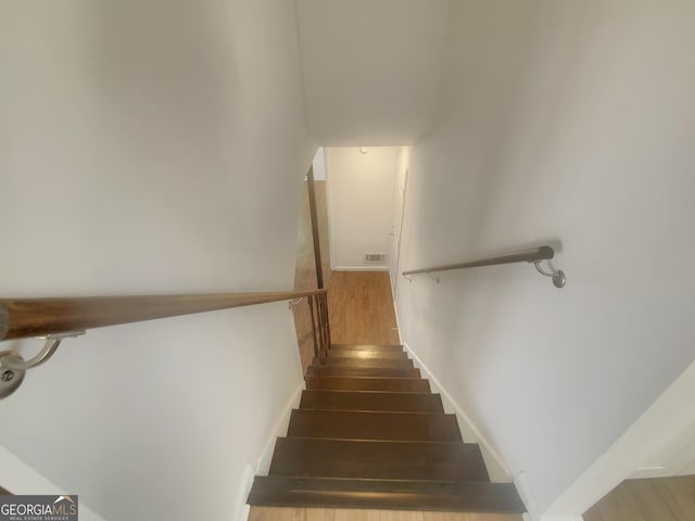 stairs with baseboards, visible vents, and wood finished floors