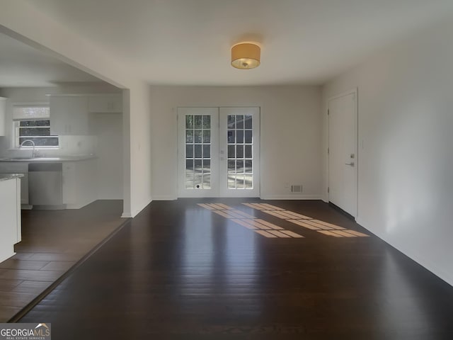 unfurnished dining area with french doors, dark wood-style flooring, a sink, and baseboards