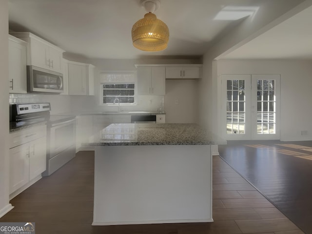 kitchen featuring appliances with stainless steel finishes, white cabinetry, dark wood finished floors, and backsplash