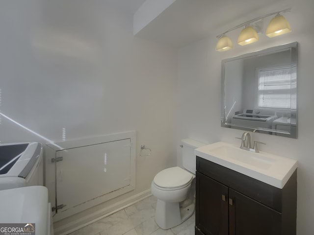 bathroom with baseboards, toilet, marble finish floor, vanity, and washing machine and dryer