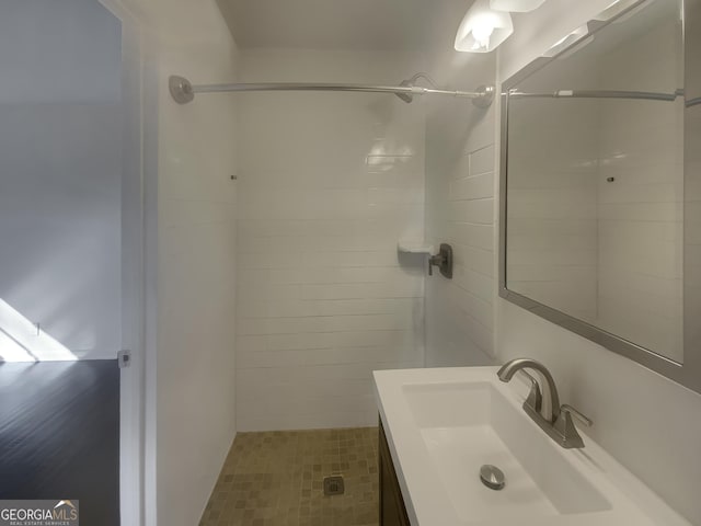 bathroom with a tile shower and vanity