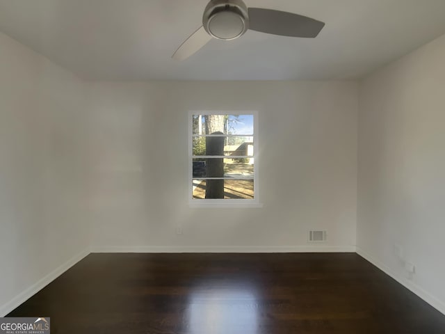 empty room featuring dark wood-type flooring, visible vents, baseboards, and a ceiling fan