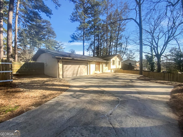 view of property exterior featuring a garage, fence, concrete driveway, and brick siding